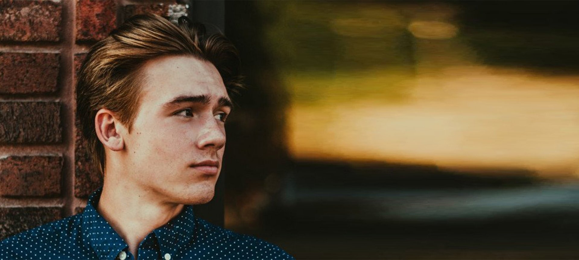 Mann mit blonden mittellangen Haaren, schaut zur Seite.